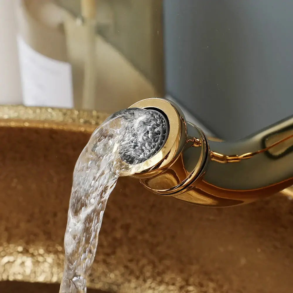 Gold-toned faucet pouring clear water into textured decorbites golden ceramic basin set for modern golden ceramic bathroom decor