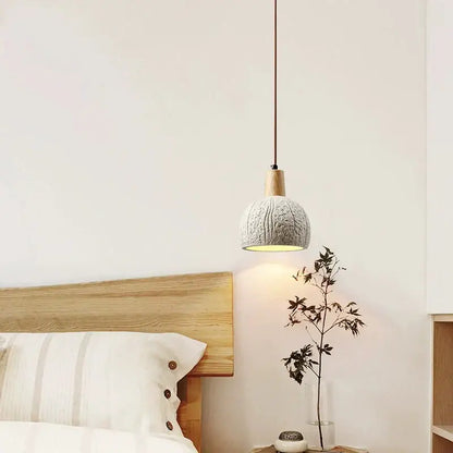 Cozy gray knitted pendant lamp with wooden top and dark cord hanging above minimalist bedside table decorbites cement chandelier