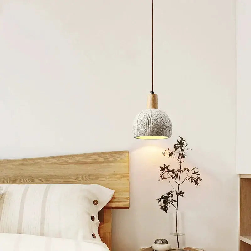 Cozy gray knitted pendant lamp with wooden top and dark cord hanging above minimalist bedside table decorbites cement chandelier