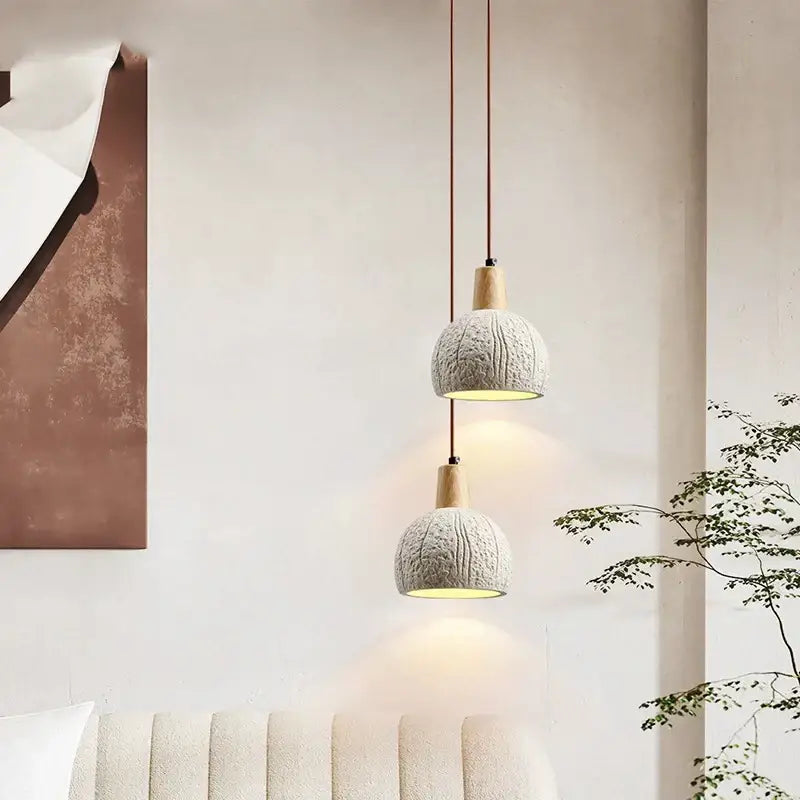 Two pendant lamps with textured light gray knitted shades and wooden tops featured in decorbites cement chandelier design