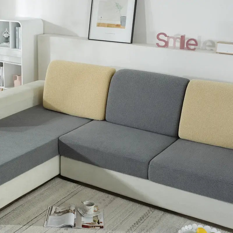Textured green and beige fabric sofa cover with elasticized edges for living room furniture protection