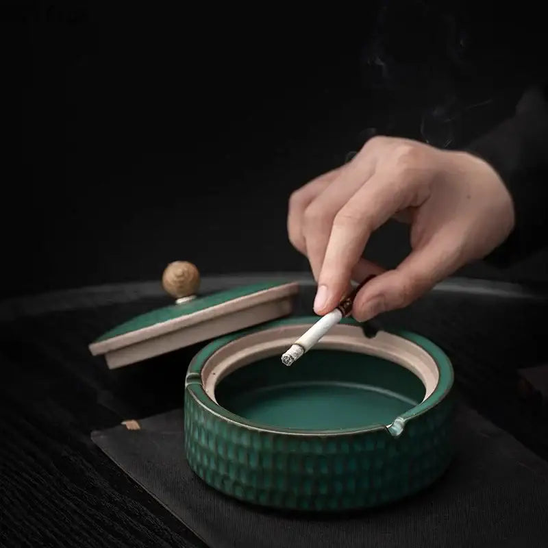 Green ceramic ashtray with textured ribbed exterior and matching lid with wooden knob for living room use