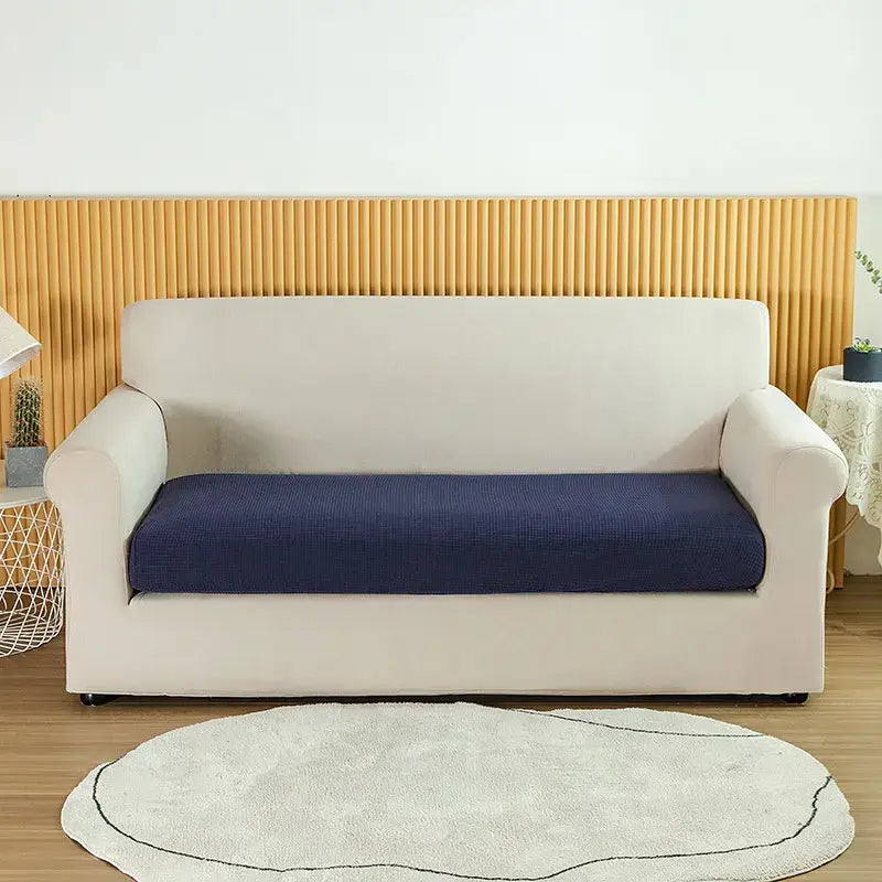 Cream-colored stretch sofa cover with navy blue textured seat cushion for living room use