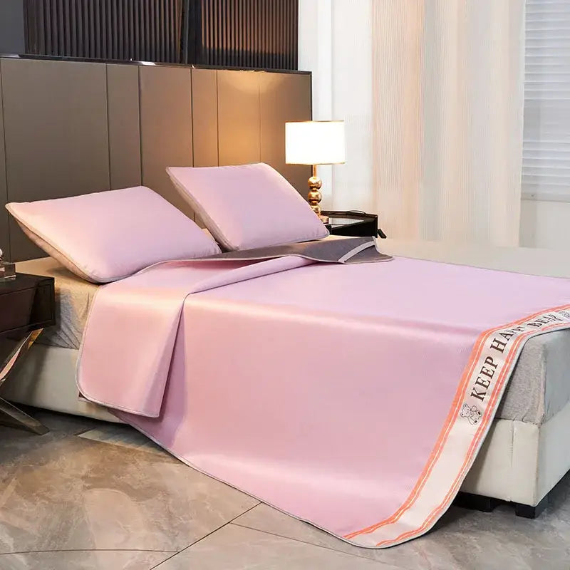 A soft pink satin bedspread with embroidered bear detail draped over a bedroom featuring a textured light blue 1800d cooling fibres bed mat pillowcases set