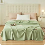 A soft mint green plush decorbites cloud comforter throw blanket with textured surface and embroidered logo corner