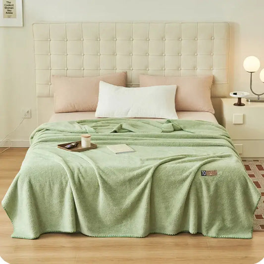 A soft mint green plush decorbites cloud comforter throw blanket with textured surface and embroidered logo corner