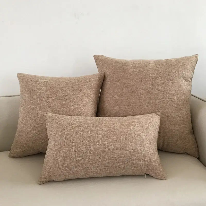 Three beige textured fabric throw pillows with woven cushion cover on decorbites ivory sofa for living room decor