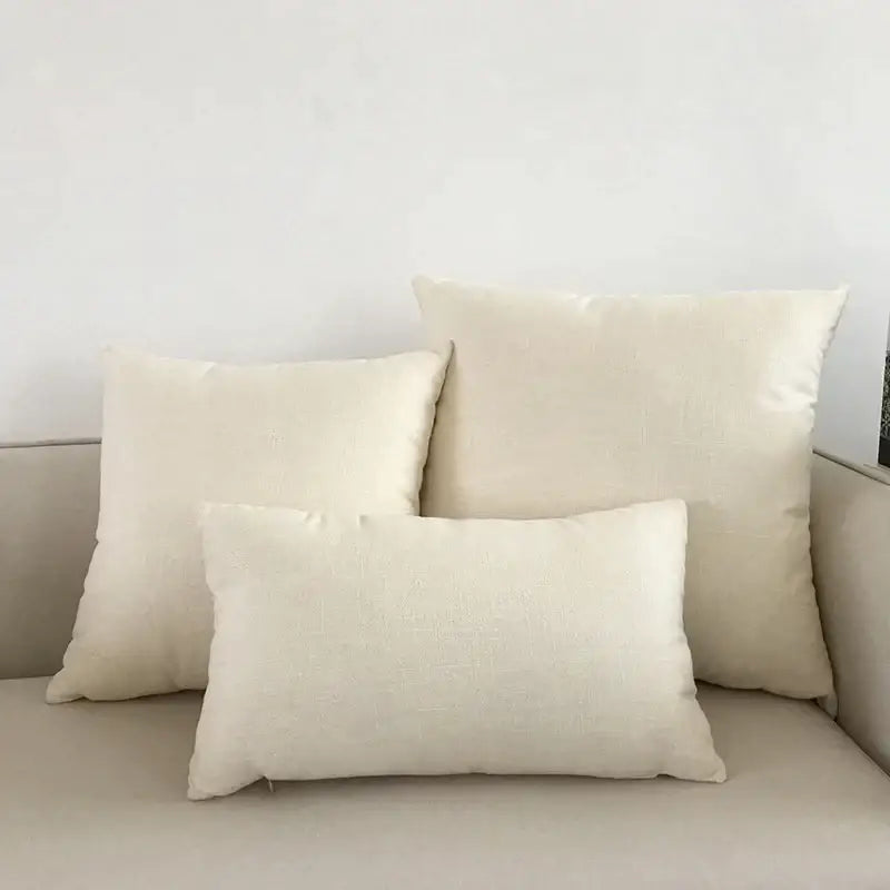 Three off-white linen pillows of varying sizes on a beige decorbites ivory sofa with textured orange cushion cover