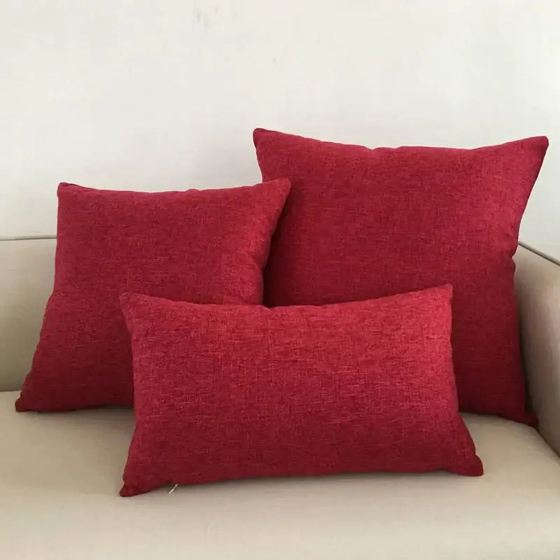 Three red textured fabric cushion covers arranged on a decorbites ivory sofa for living room decor