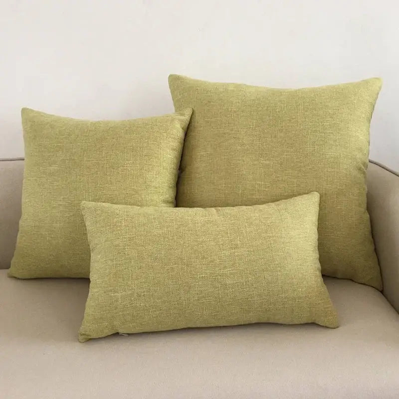 Three sage green linen-textured throw pillows on a beige decorbites ivory sofa complementing ivory sofa cushions and cushion covers