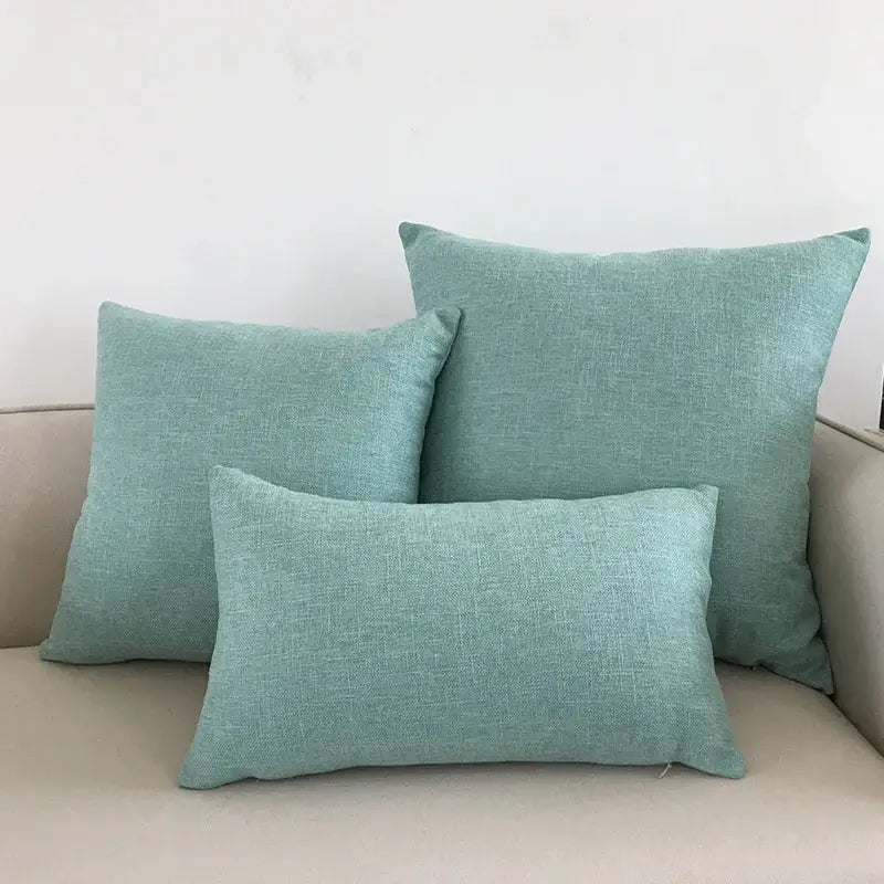 Set of three teal linen throw pillows in varying sizes on beige decorbites ivory sofa with ivory sofa cushion cover