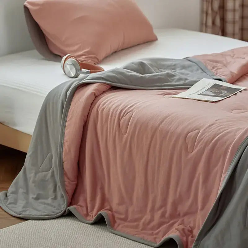 A soft two-toned pink and gray decorbites cotton summer comforter with plush texture and subtle stitched patterns