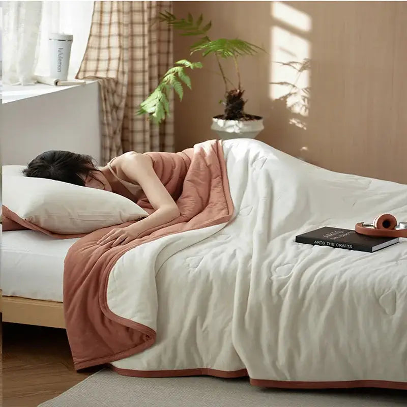 Soft cream-colored decorbites cotton summer comforter with terracotta border draped on bed for cooling bedroom use