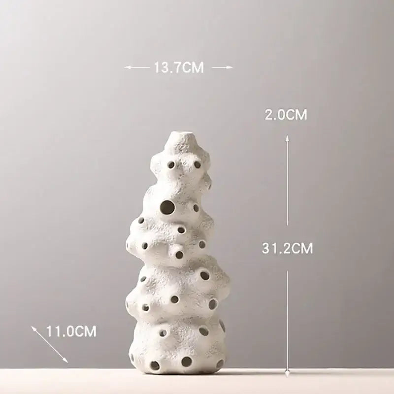 White textured ceramic vase set with stacked organic form and circular holes featuring artificial flowers for living room