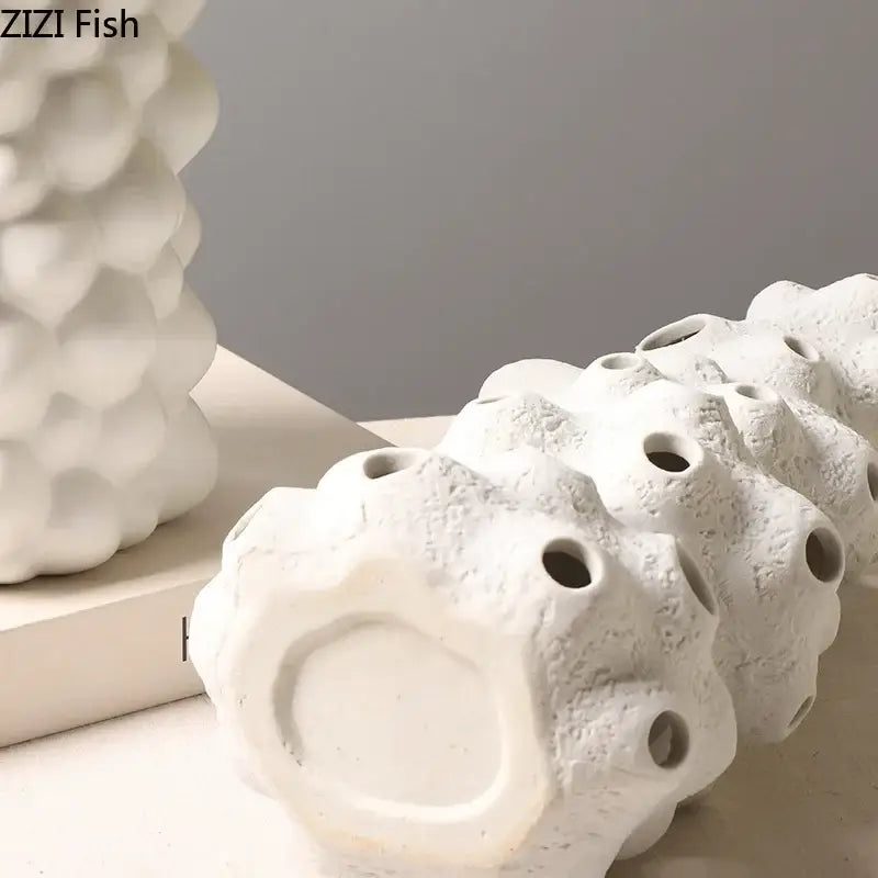White ceramic vase set with textured porous coral sculpture and artificial flowers for living room decor