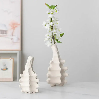 White ceramic decorbites ceramic vase with textured segmented design and narrow neck holding white blossoms for home decor