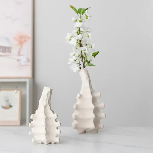 White ceramic decorbites ceramic vase with textured segmented design and narrow neck holding white blossoms for home decor