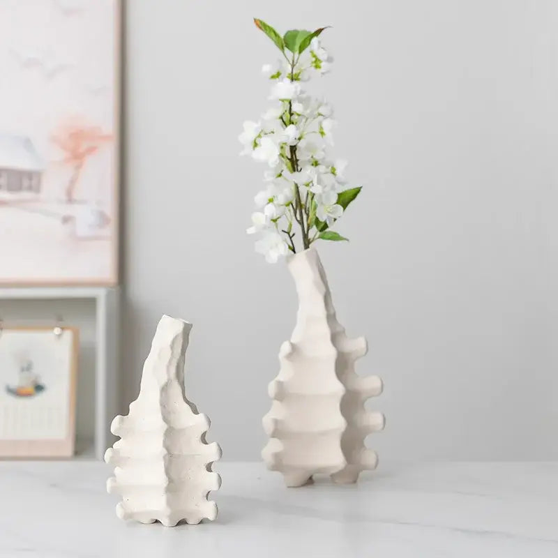 White ceramic decorbites ceramic vase with textured segmented design and narrow neck holding white blossoms for home decor