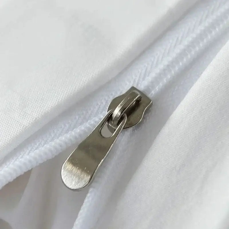 Silver-toned zipper pull on white fabric of textured white pom pom quilt cover set for bedroom bedding