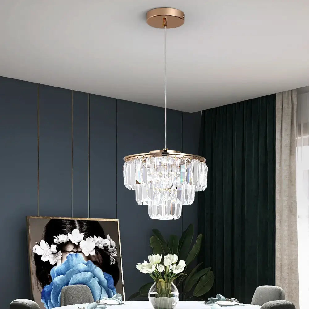 A modern tiered gold crystal led pendant light with rose gold finish and cascading clear glass prisms for dining room decorbites crystal led