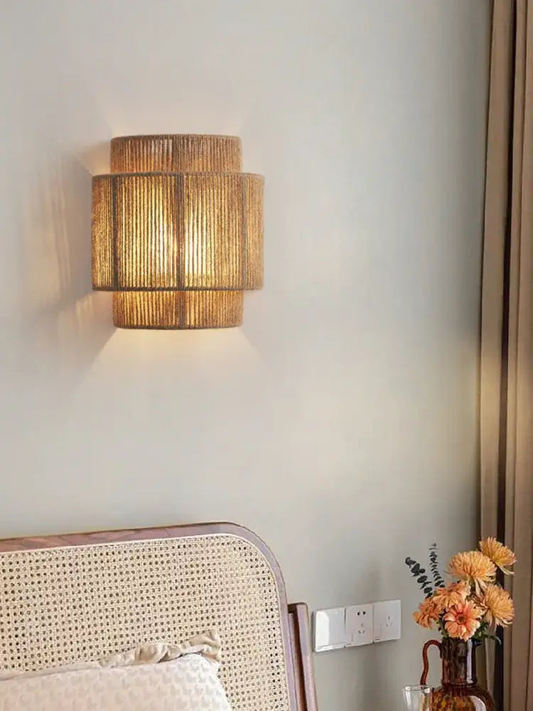 A warm-toned tiered wall lamp crafted from woven natural rattan with hemp rope decorbites for bedroom and living room