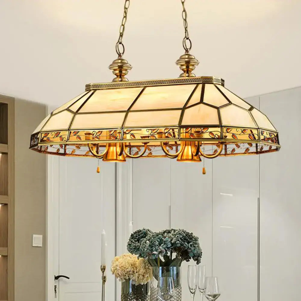 Gold-toned tiffany-style pendant light with amber cream stained glass panels and leaf motifs for restaurant island lighting