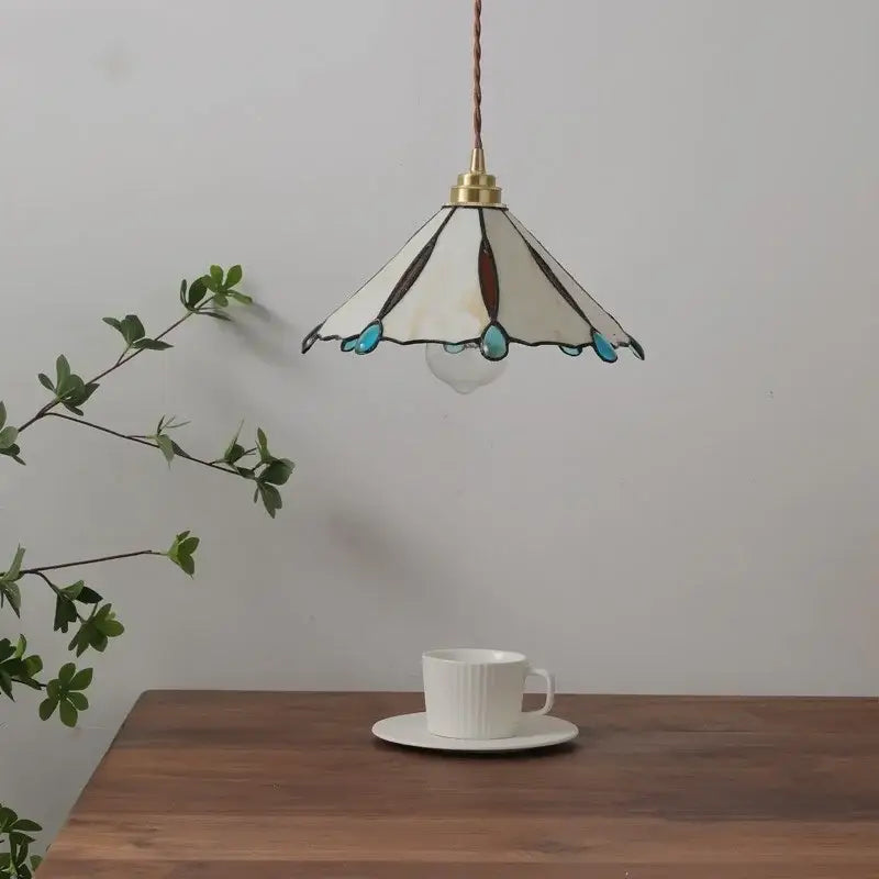 Tiffany stained glass copper led pendant lamp with cream brown and turquoise accents hanging above wooden table