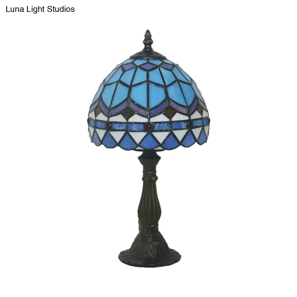 A tiffany stained glass table lamp with blue and pink dome shade and ornate dark bronze base for 110v-120v use