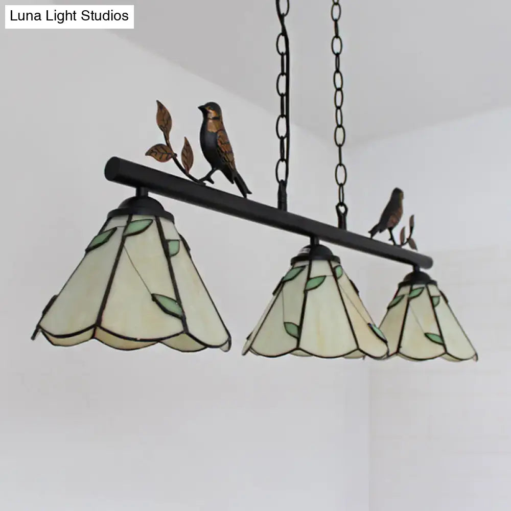 Three-tiered tiffany style pendant light with cone stainless glass shades, bird accent, and black wrought iron frame for island lighting