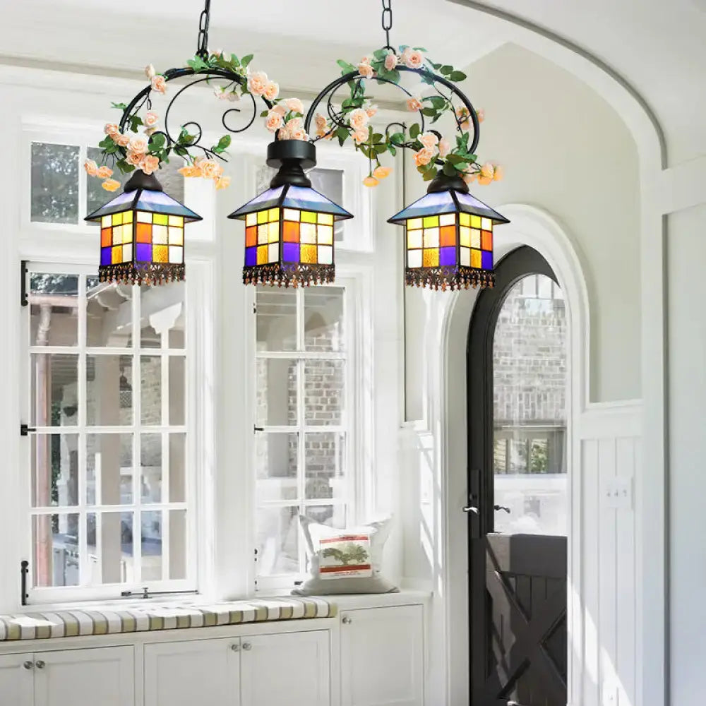 Three ornate stained glass lanterns with clear blue and yellow panels hang on a decorbites™ tiffany style island light fixture