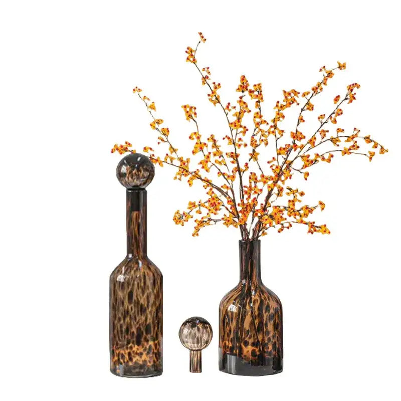 A tall amber-tinted leopard print glass decanter with a spherical stopper for decorbites leopard print living room decor