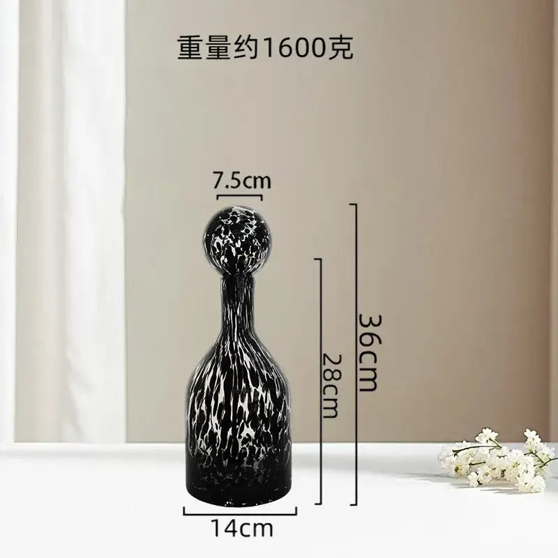 A sleek black glass decanter with a white marbled pattern and rounded stopper as decorbites leopard print decor