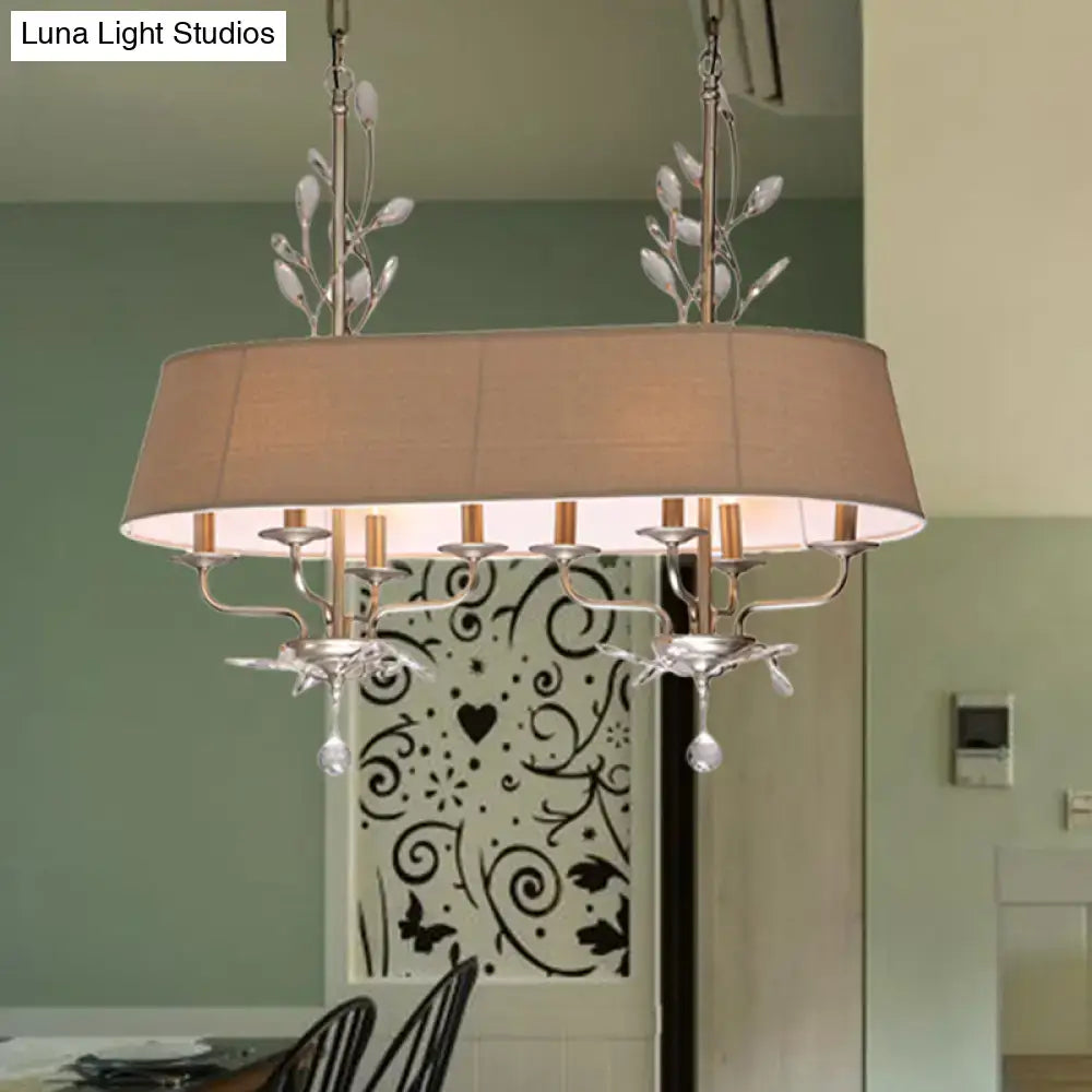 Silver-toned traditional chandelier with beige fabric shade and crystal leaf accents for dining room island lighting