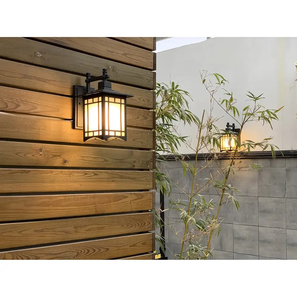 Traditional black led wall lamp garden lantern with frosted glass and warm glowing light mounted on wooden siding