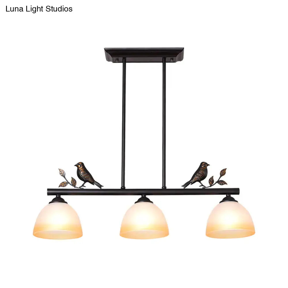 Black wrought iron ceiling light with three white glass shades and decorative bird perches for dining room island