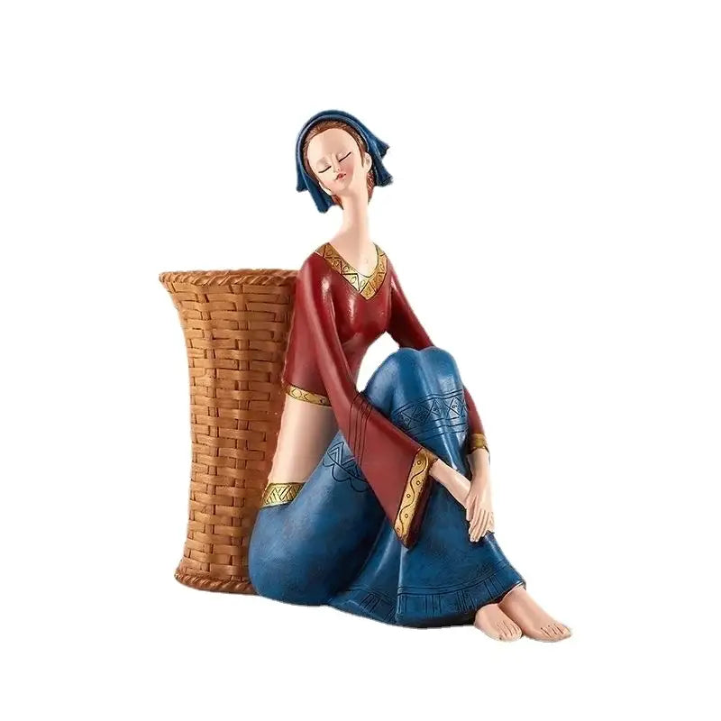 Detailed resin ornaments of a woman in a red and blue medieval dress seated beside a woven basket for decorbites cute girls storage