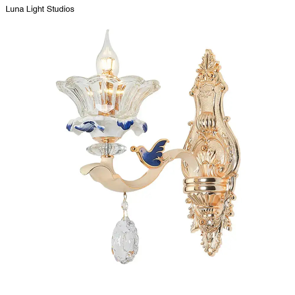 Traditional brass crystal flower wall sconce light with gold finish, clear glass shade, blue enamel bird, and crystal pendant