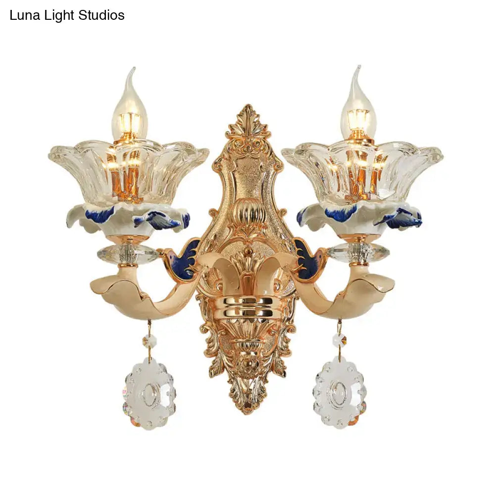 Traditional brass wall sconce light with gold-toned crystal flower shades and blue clear glass droplets for living room