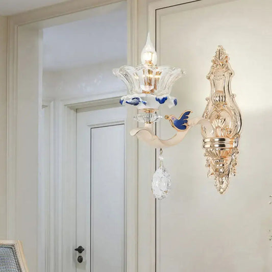 Elegant gold-toned brass wall sconce light with clear glass flower design blue bird motif and dangling crystal teardrop
