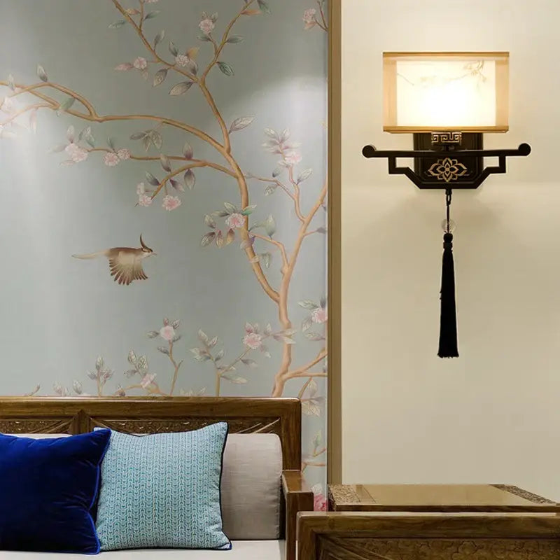Black lacquered wall lamp with square glowing fabric shade and ornate tassel decorbites elegant fabric wall decor