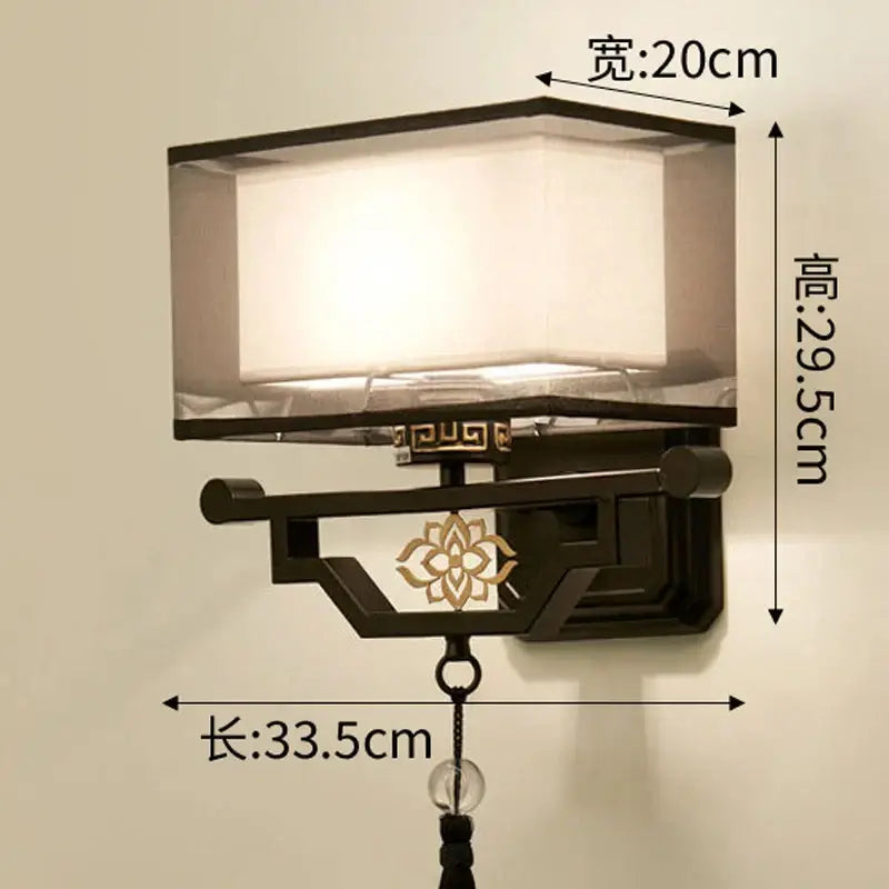 Black wrought iron wall lamp with translucent frosted glass shade and ornate gold floral decorbites elegant fabric design