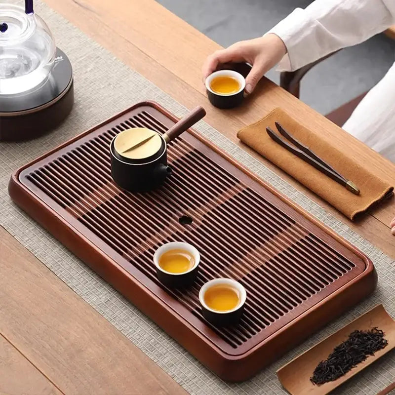 Traditional brown bamboo tea tray with water storage featuring a rectangular wooden design and parallel drainage grooves