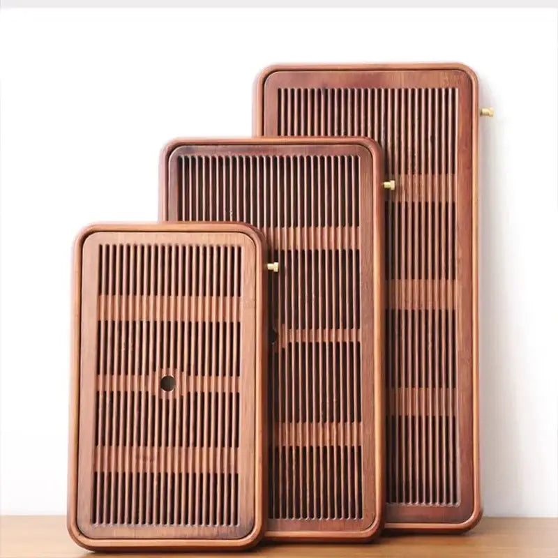Set of three traditional brown bamboo tea trays with vertical slats brass accents and water storage for dining room use
