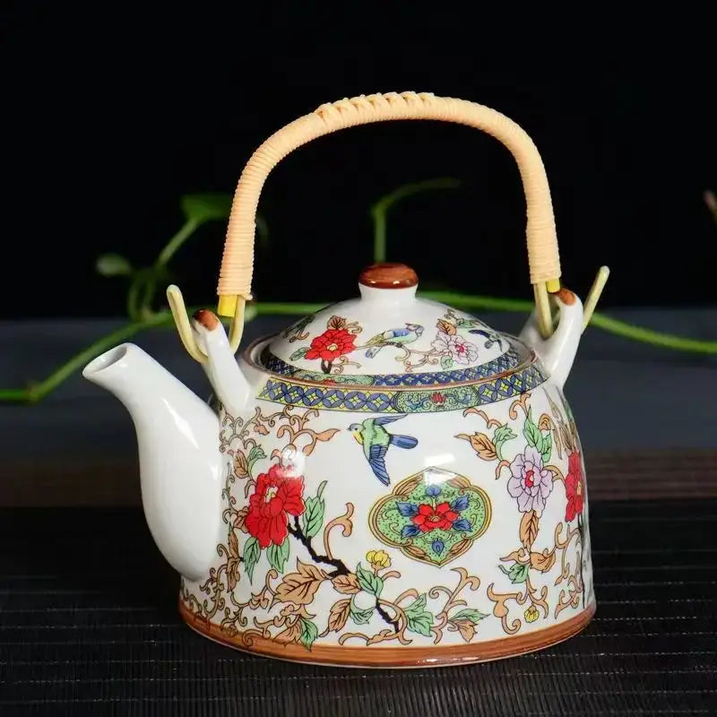 Traditional chinese white porcelain tea pot with woven bamboo handle and colorful floral and bird motifs for dining room decor