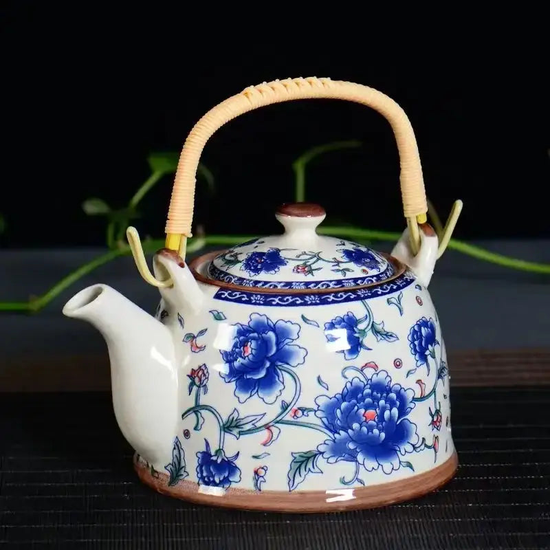 Traditional chinese white porcelain tea pot with blue floral patterns and woven bamboo handle for dining room decor
