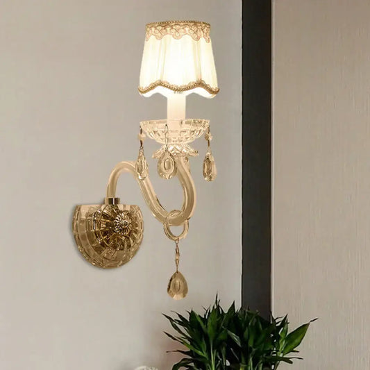 Elegant gold-toned traditional candle wall lamp with crystal accents and a lace-trimmed cream lampshade for bedroom use