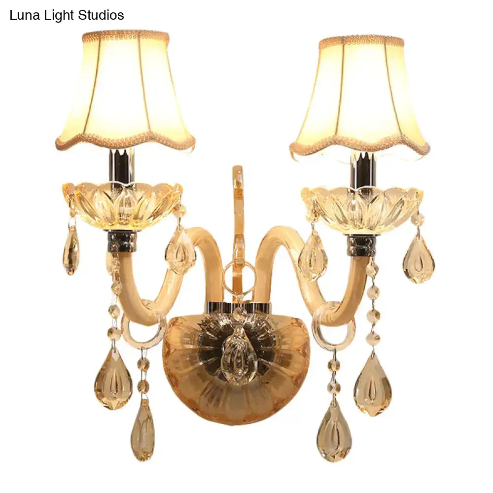 Traditional gold crystal wall sconce with two arms, fabric shade, and dangling teardrop crystals for bedroom lighting
