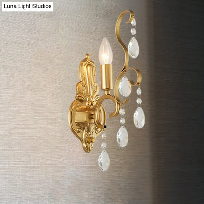 Traditional gold metal candle wall lamp with ornate design and dangling crystal teardrop pendants for living room use