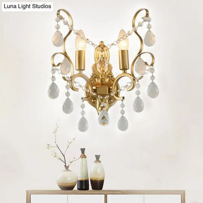 Traditional gold metal candle wall lamp with ornate design and dangling teardrop crystal pendants for living room use