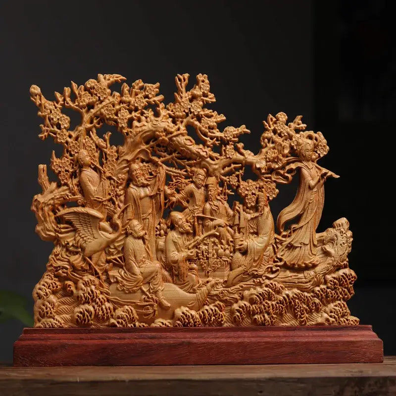 A finely carved wooden eight immortals sculpture with detailed figures under blossoming trees on a reddish-brown base